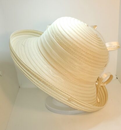 Cream wide brim hat with a flower and satin ribbons. View of back.