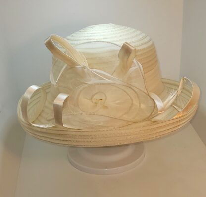 Cream wide brim hat with flower and satin ribbons. Front view.