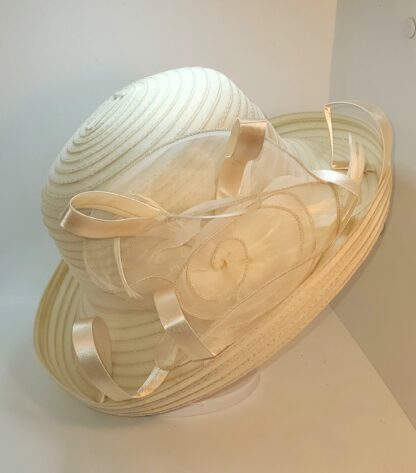 Cream wide brim hat with flower and satin ribbons. left side view.